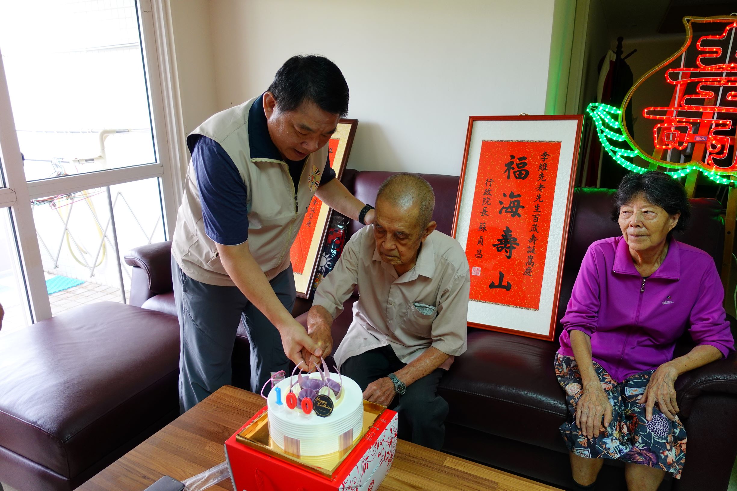 黃處長握著李爺爺的手切蛋糕，祝其生日快樂