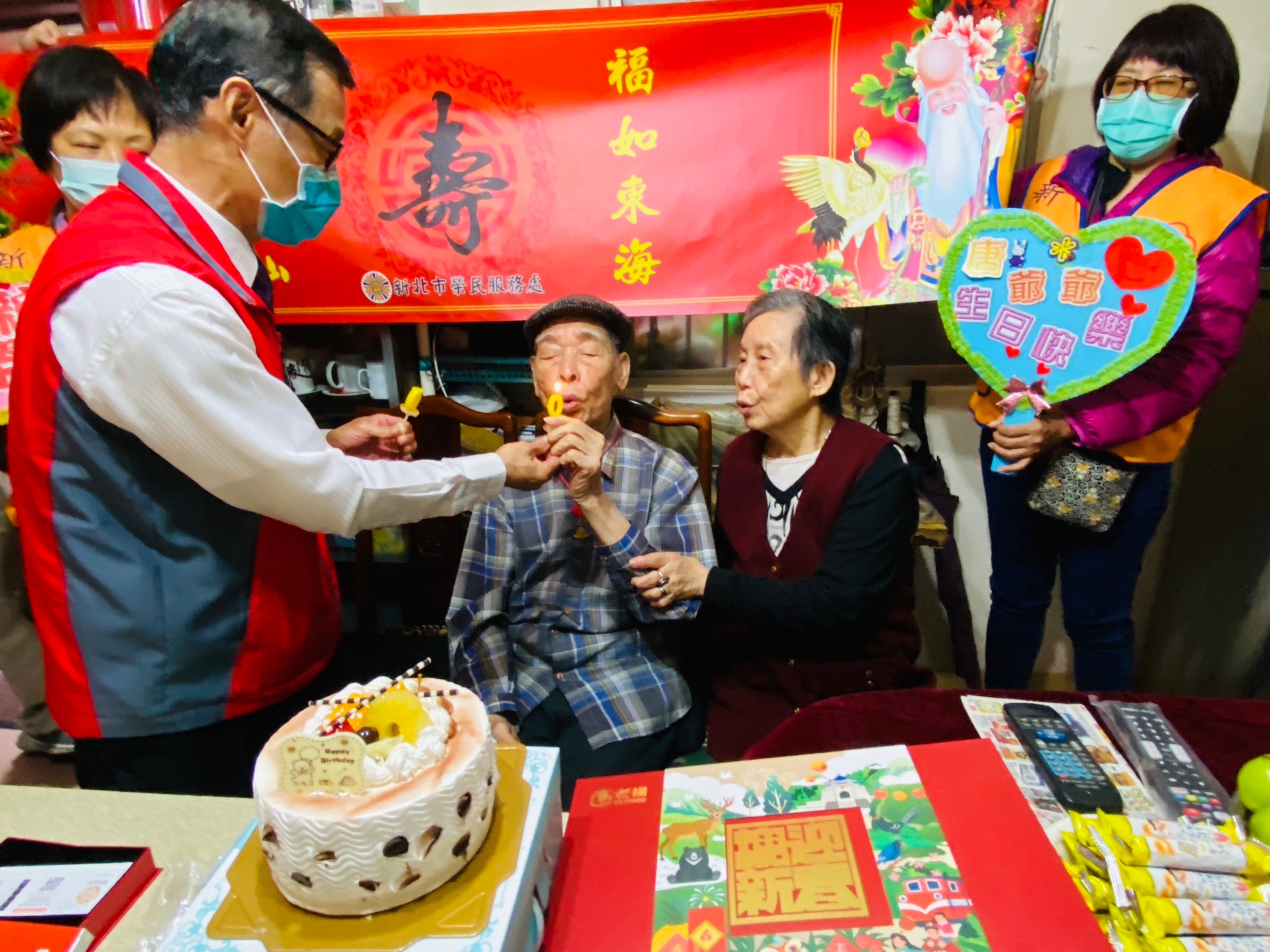 周興國處長(左)請唐爺爺(中)吹蠟燭與唐奶奶一同慶賀百歲生日