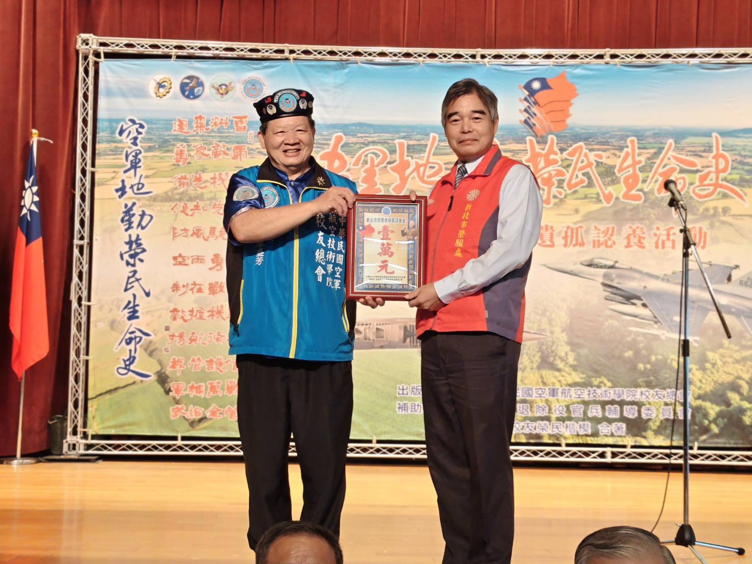 廖盛芳總會長(左)代表捐贈榮民遺孤學子認養金,由林處長代表受贈。