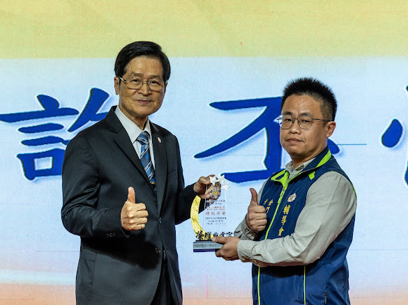 圖五嚴德發主任委員(左)頒發許丕懌助理員(右)績優運用單位承辦人獎項