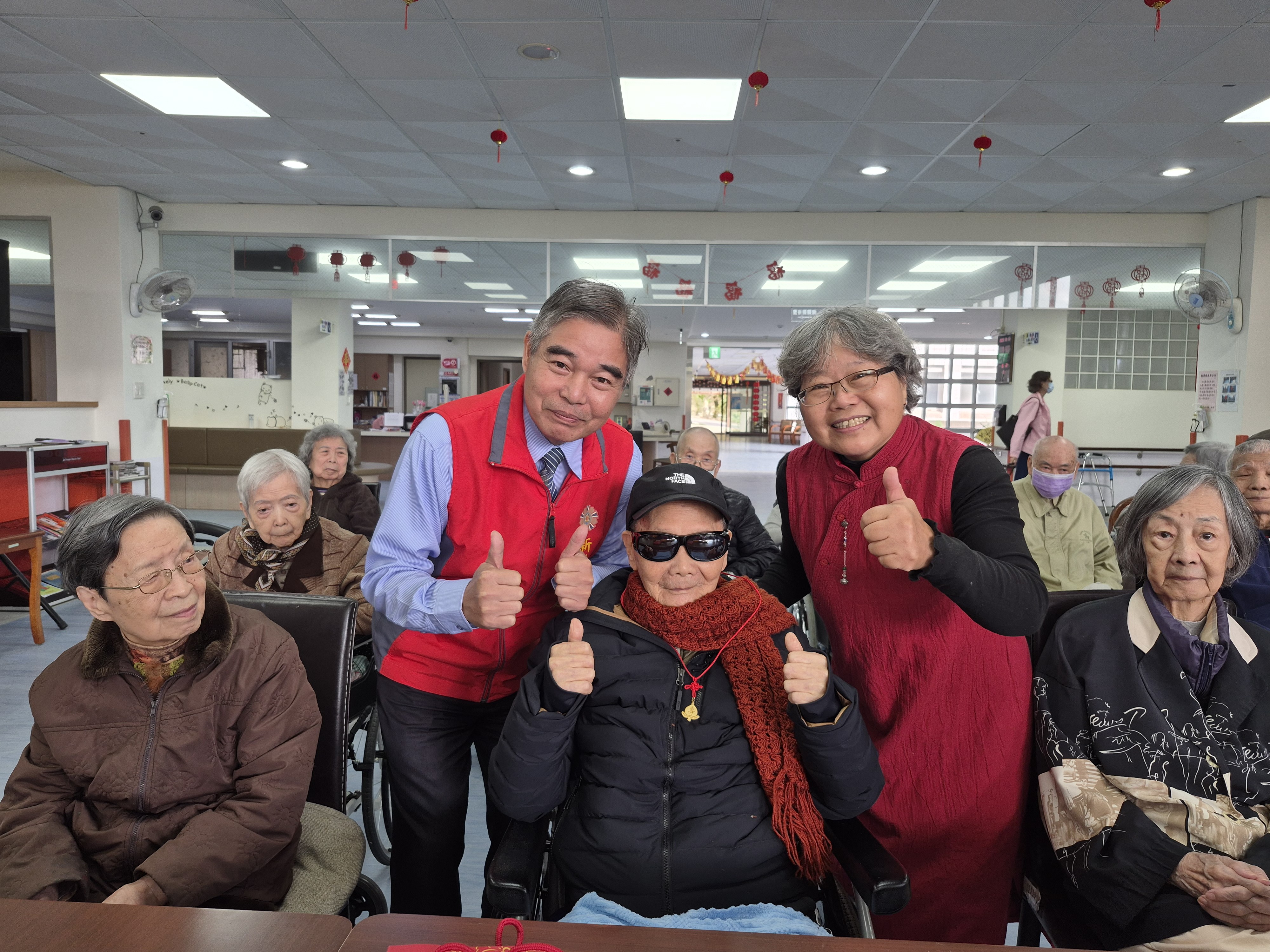 林處長(左2)與翠柏中心主任王儀玲(右2)一起為金爺爺(中)戴上輔導會致贈的金壽桃。