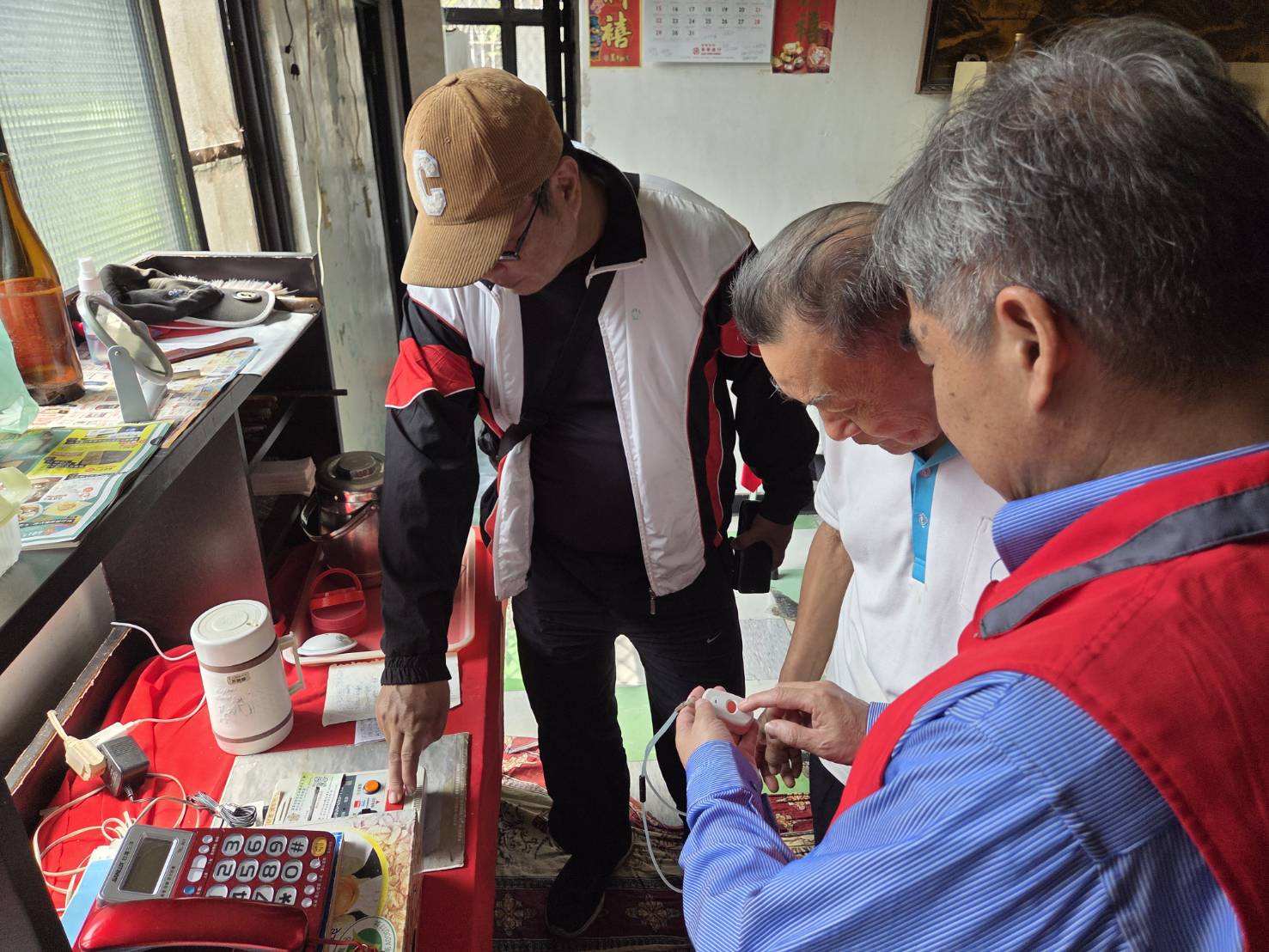 新北市榮民服務處處長林振生(右)訪視榮民劉伯伯(中),並關心其生活近況並實地測試遠距居家照顧系統,功能正常。