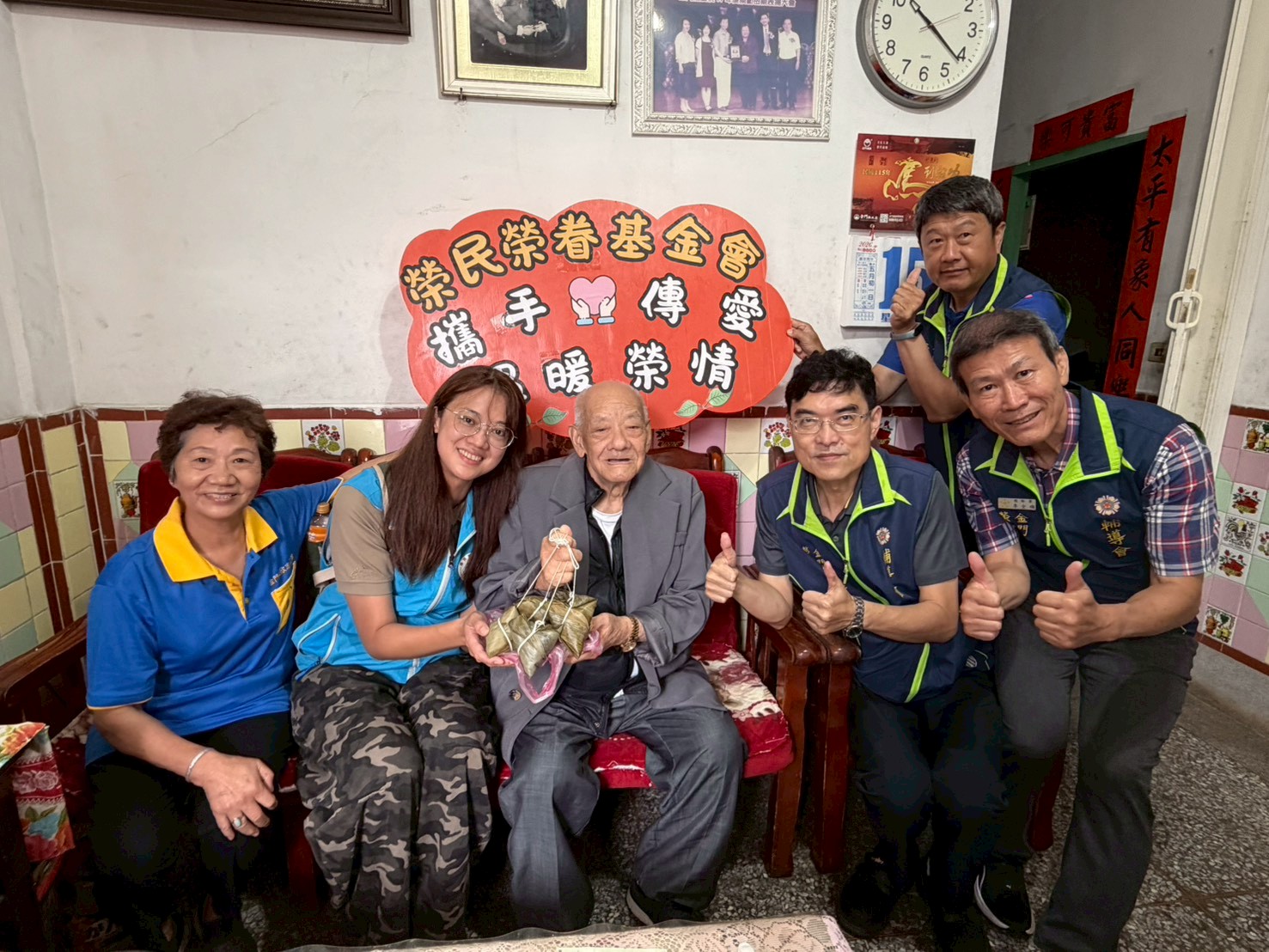圖五彭致和副處長(右2)及榮基會巫安妮專員(左2)致贈榮民吳爺爺(中)端節肉粽