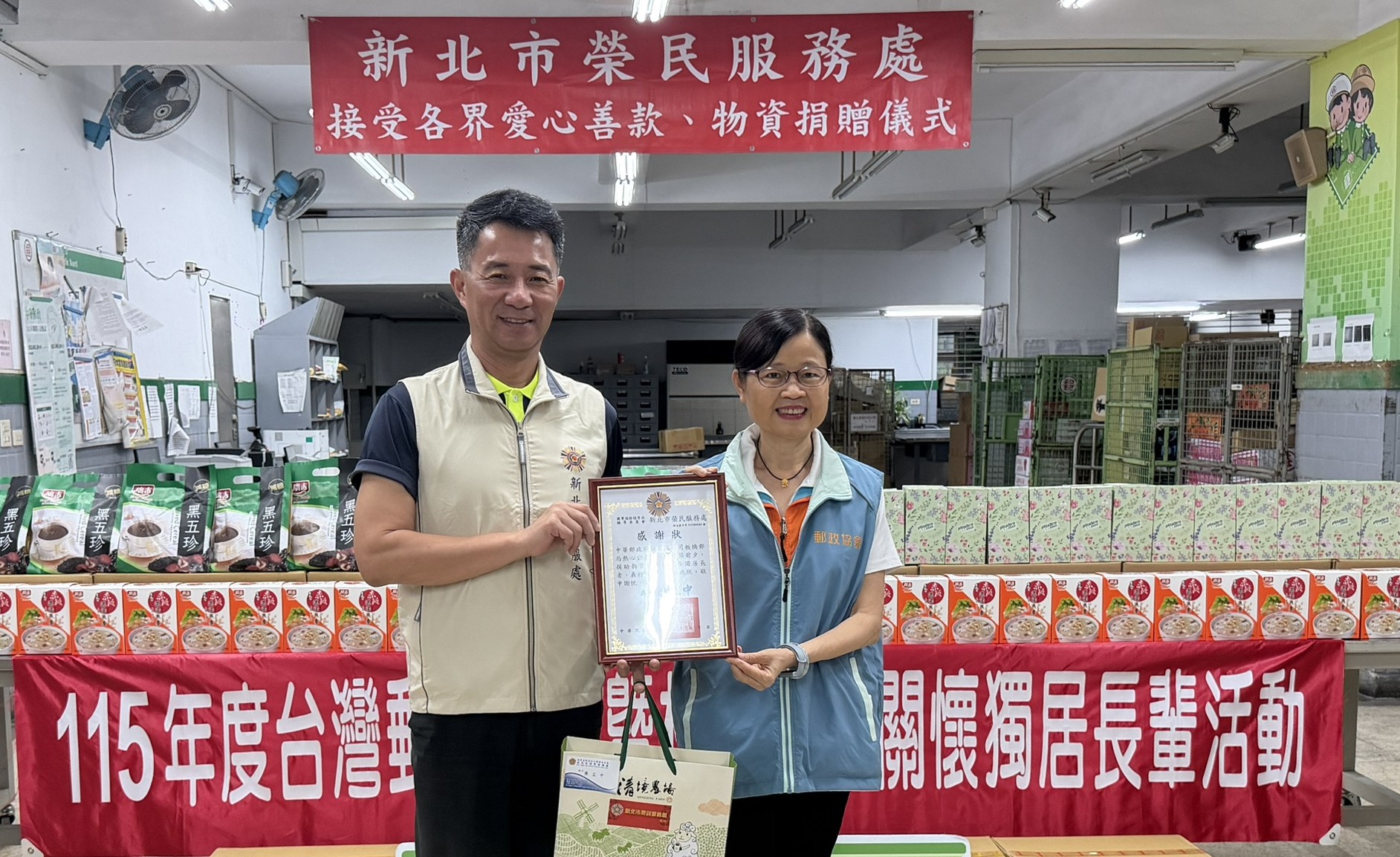 板橋郵局捐贈端節愛心物資,由板橋郵局胡美惠局長(右)代表捐贈,新北市榮服處陳立中處長(左) 代表受贈,並回贈感謝狀以表謝忱。
