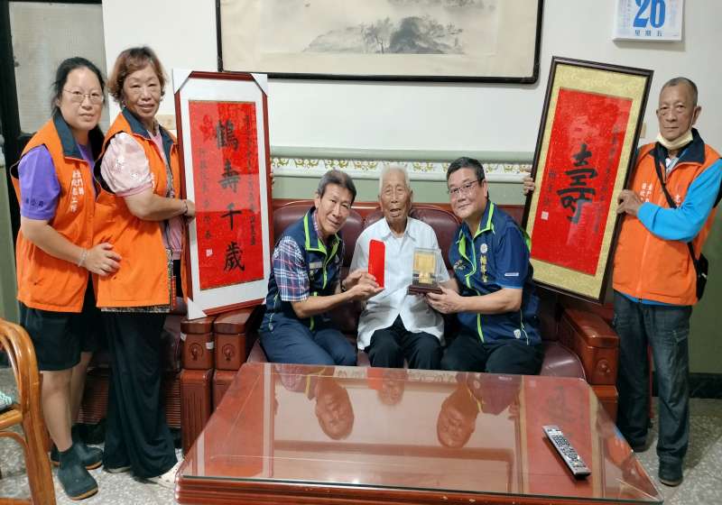 圖一劉信義處長(右2)致贈金壽桃,李全順總幹事(左3)代贈祝壽金
