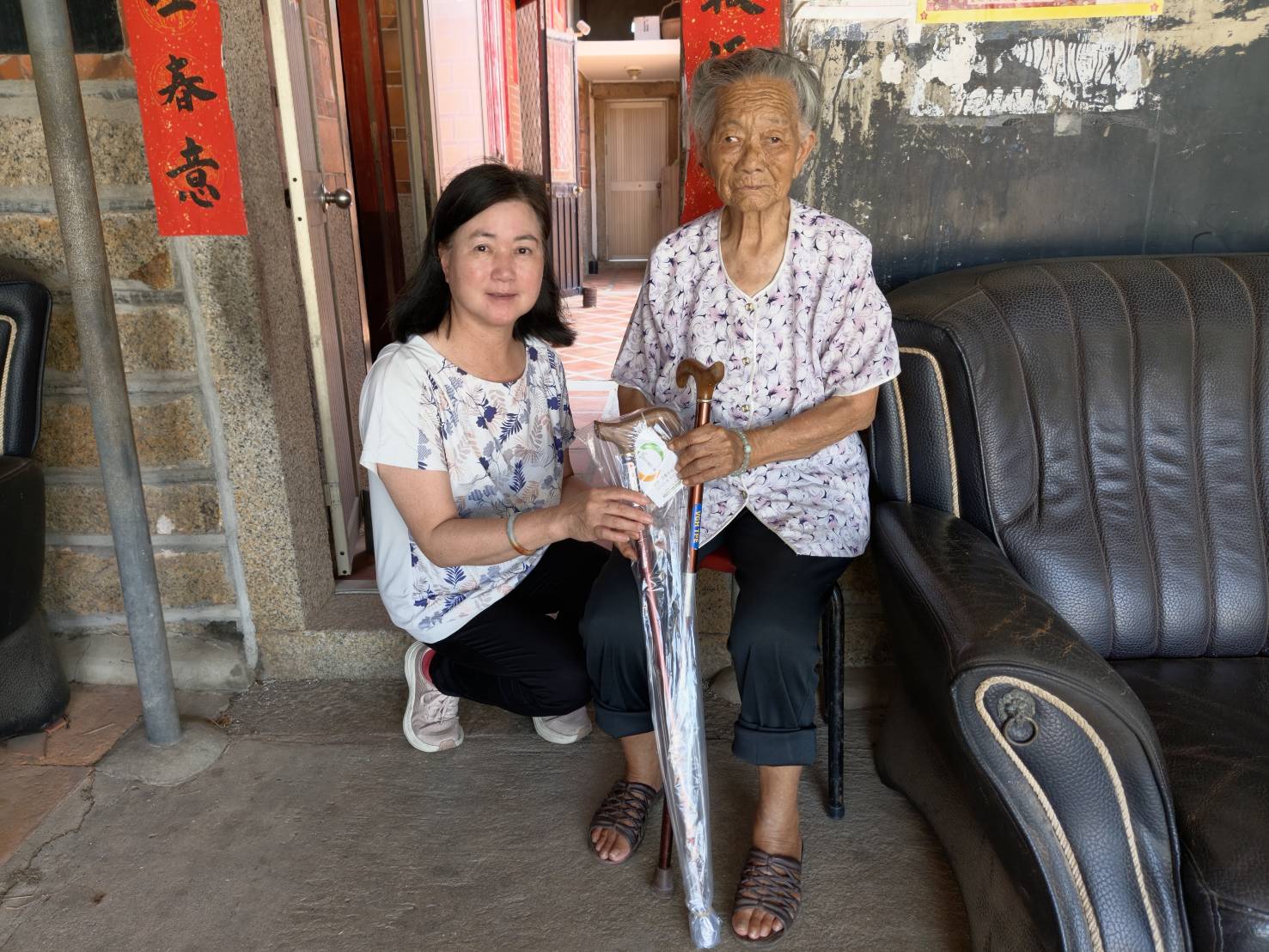 圖四金寧志工隊林玉寶隊長(左)協助送交拐杖予陳奶奶並轉達輔導會關懷之意