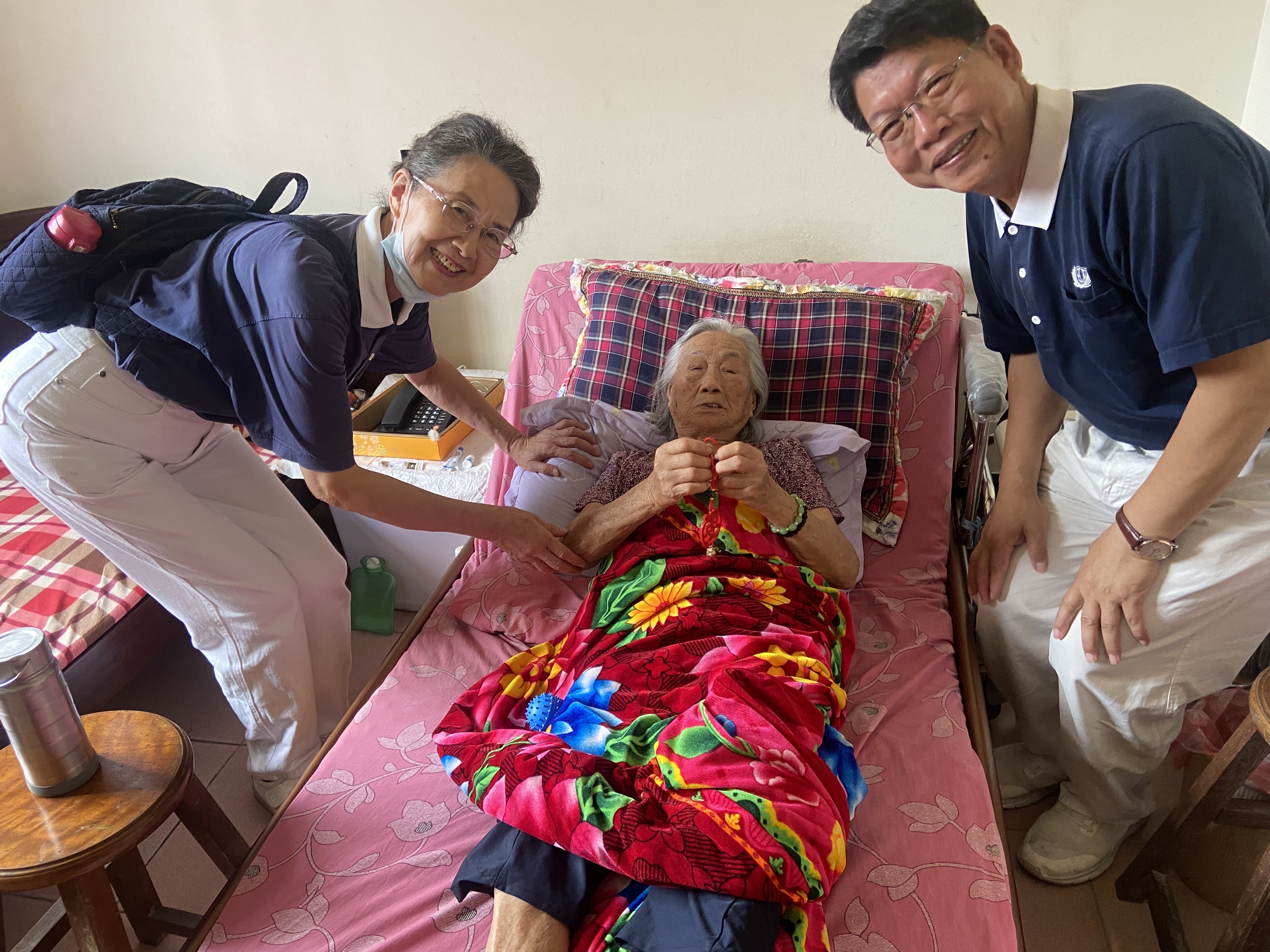 圖一金門分會洪松柏分會長(右))與個案黃阿嬤(中臥)家訪評估後合影