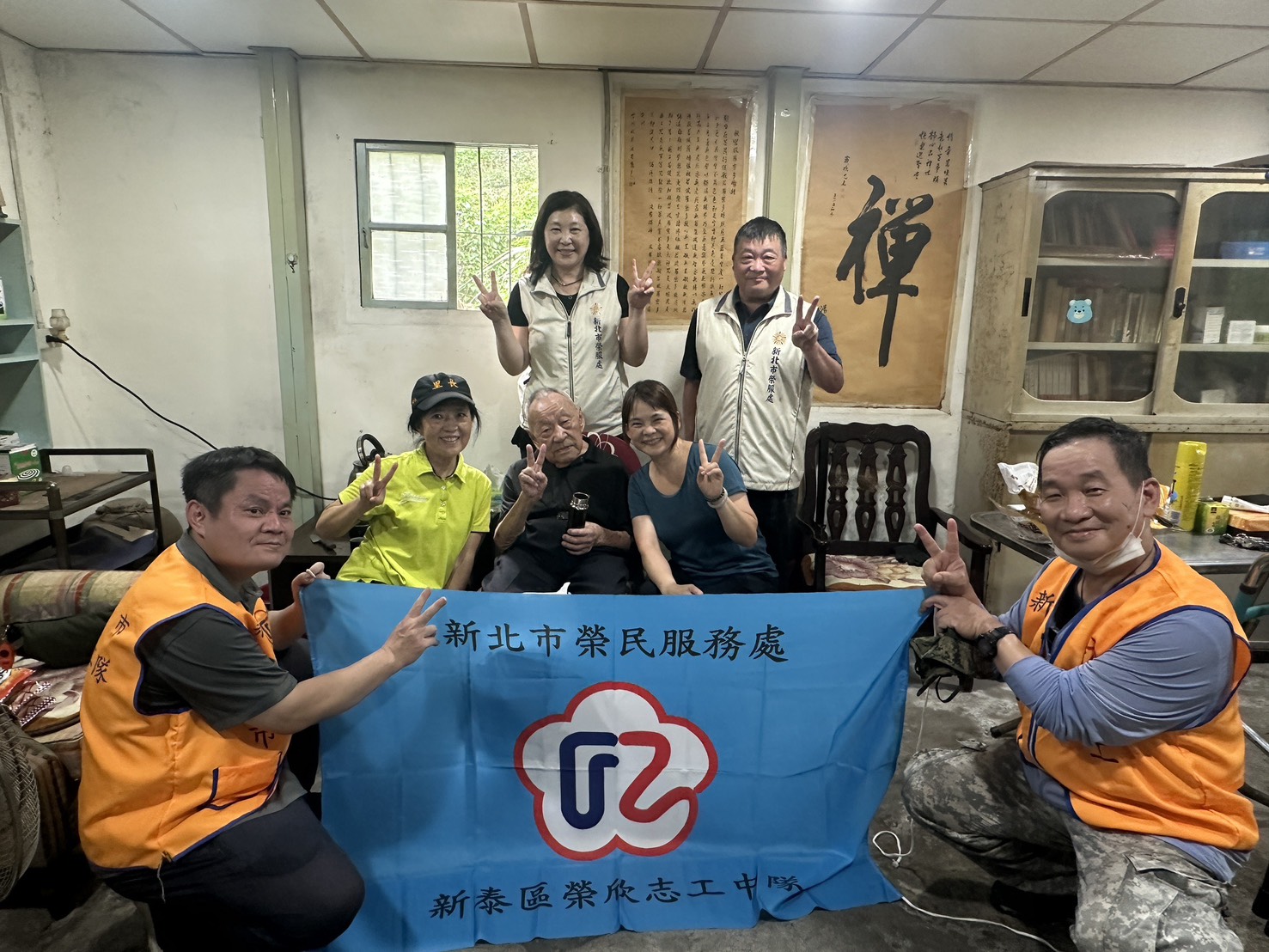 新北榮服處總幹事吳曉慧(第三排左)偕同輔導員、榮欣志工及里長潘素娥(第二排左)、鄰長陳米伸(第二排左三)關懷榮民湯伯伯(第二排左二),祝福長輩健康平安。