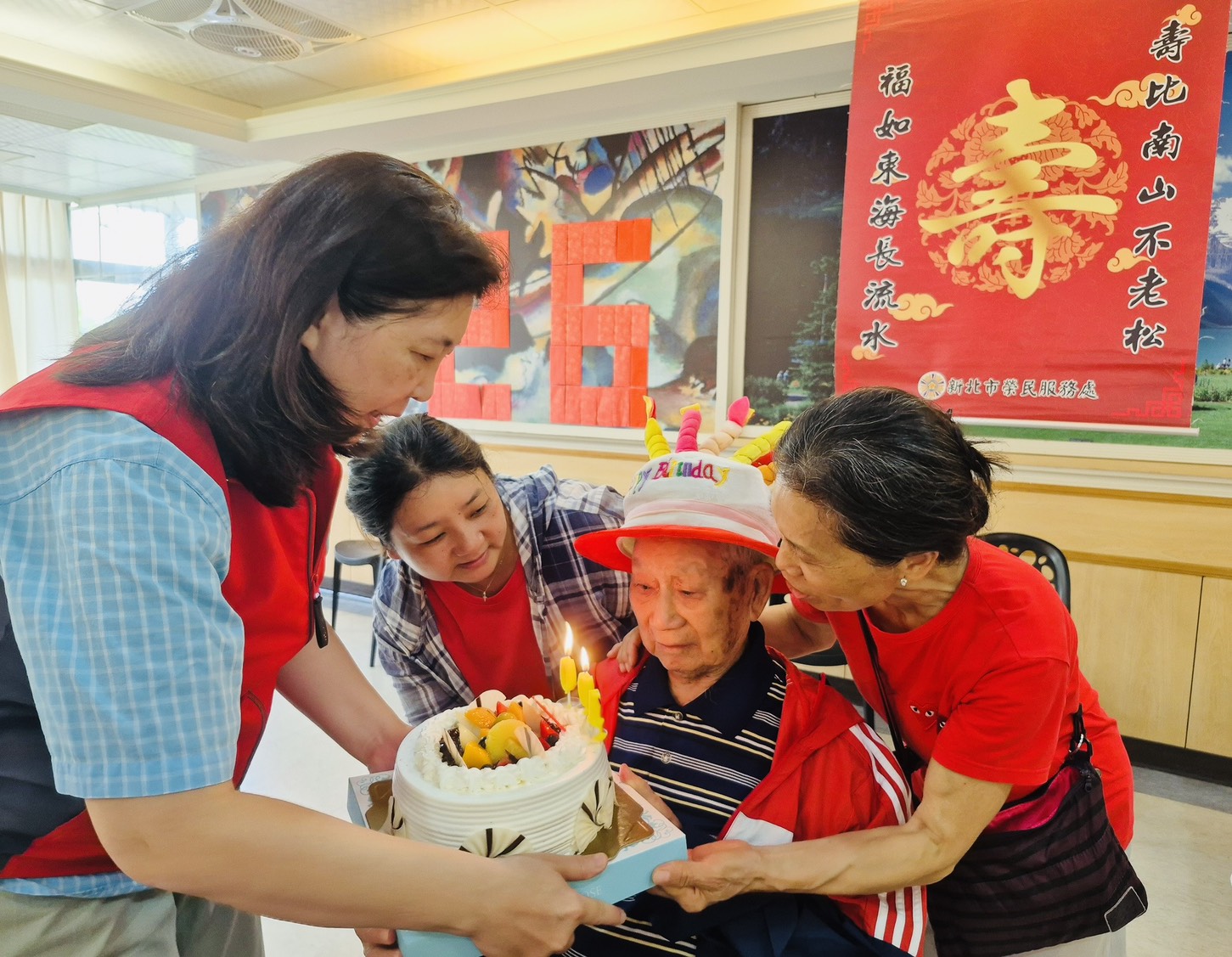 ▲毛伯伯(右2)吹熄生日蠟燭,吳總幹事(左1)手捧蛋糕。/新北市榮服處提供。