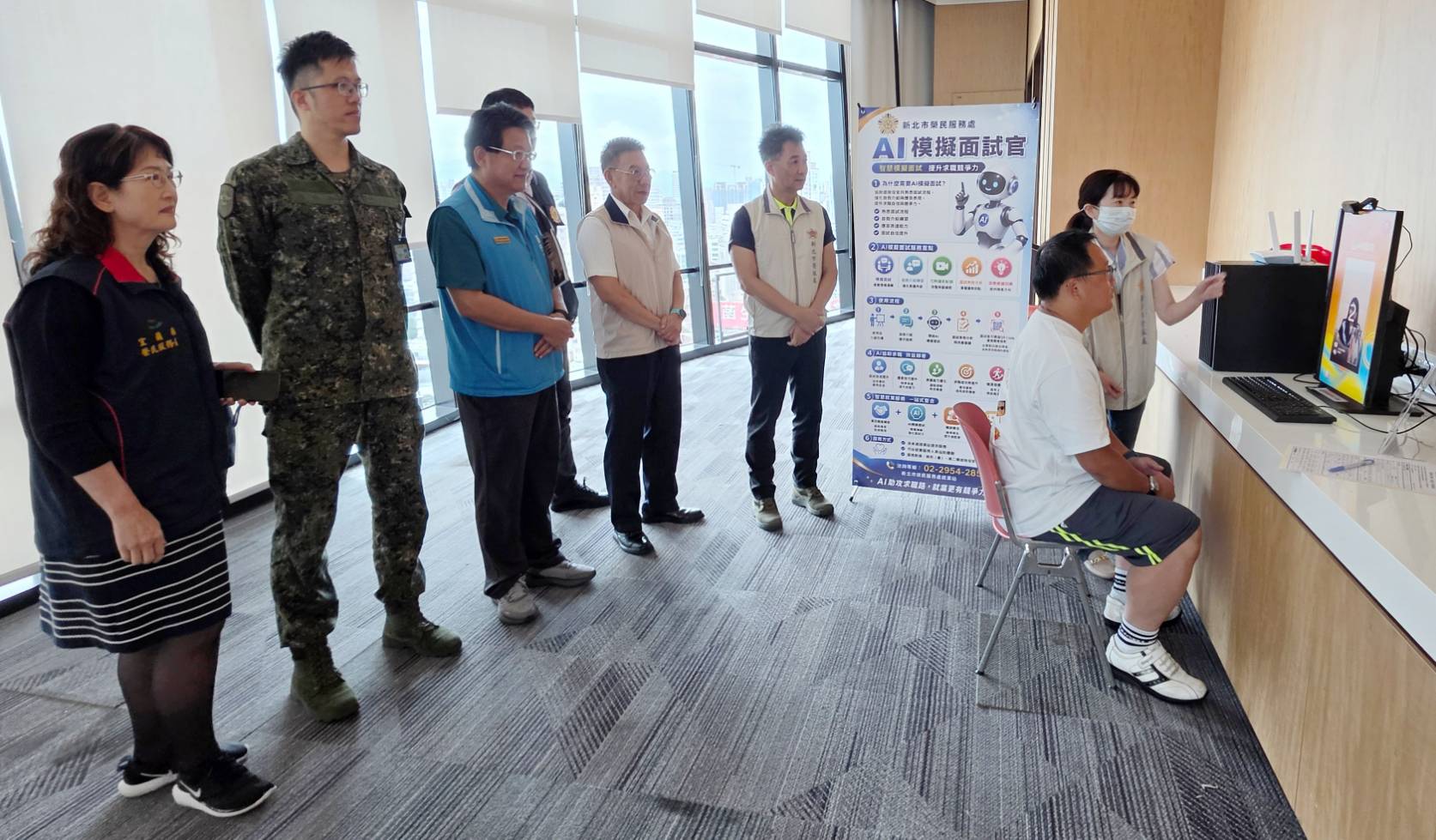 ▲新北市榮服處於活動現場提供「AI模擬面試」服務,透過實際面試情境演練,協助屆退官兵強化求職準備與面試信心。李建學專門委員(立者右3)、陳立中處長(立者右2)實地瞭解操作情形。/新北市榮服處提供