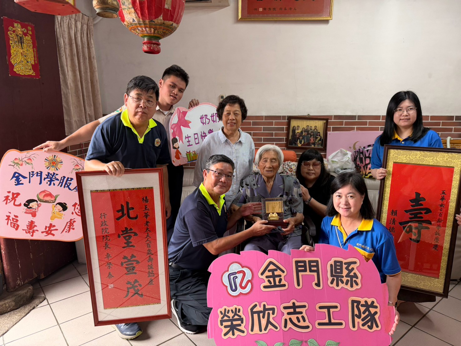 圖一劉信義處長(蹲左1)致贈金壽桃及壽屏予楊玉華阿嬤(坐左2)