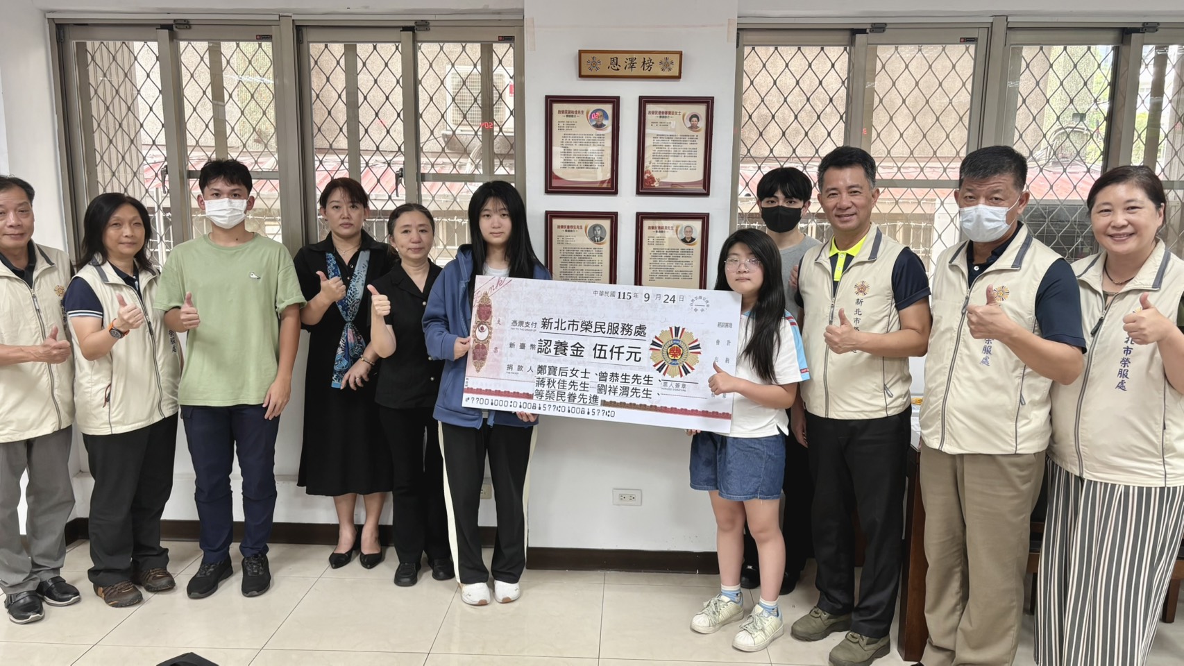 ▲新北市榮民服務處處長陳立中(右三)、副處長楊懷博(右二)及總幹事(右一)頒發每月認養金每人五千元,與向學子女及眷屬代表合影。 /新北市榮民服務處