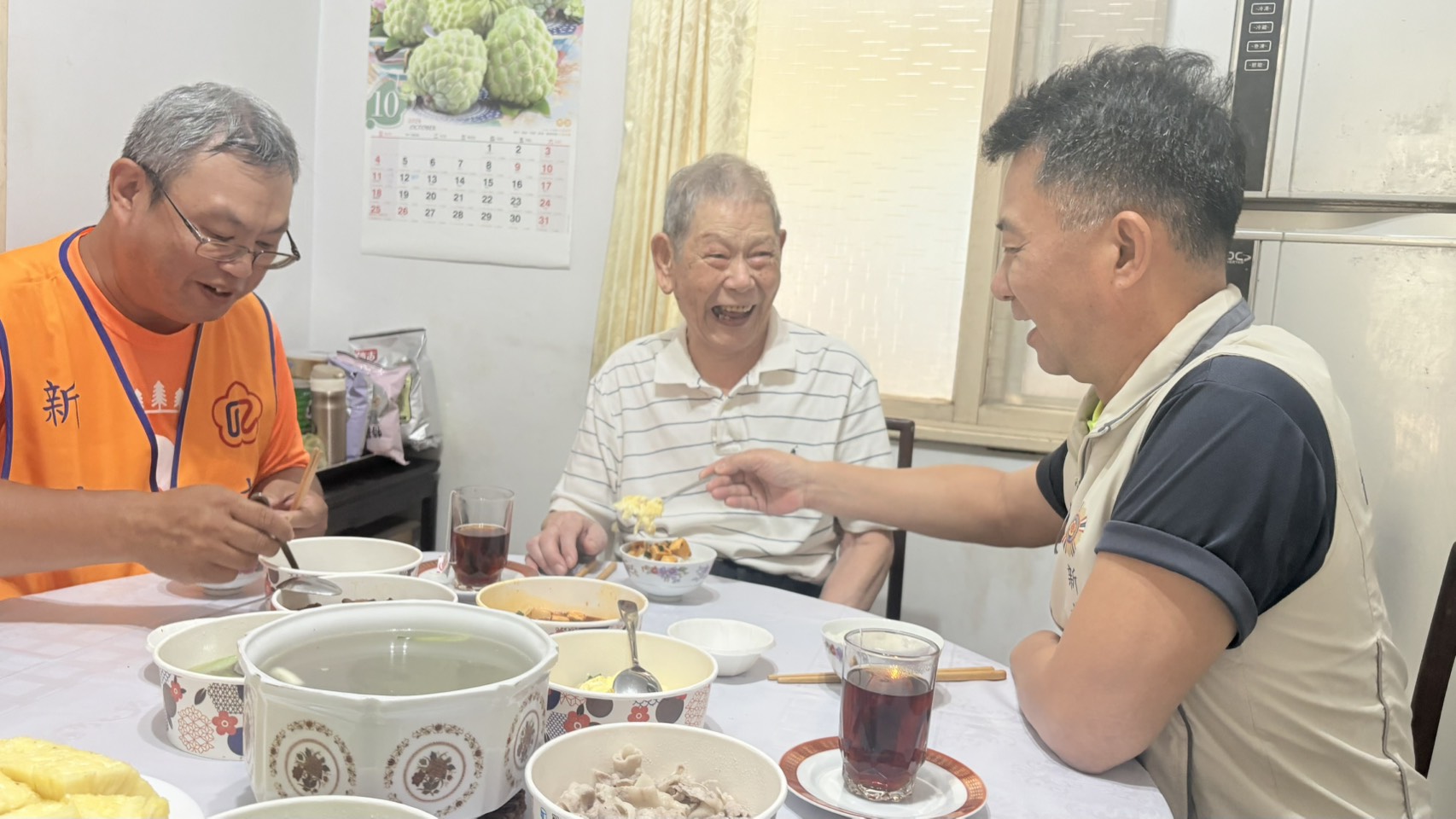 ▲處長陳立中(右)專注聆聽榮民周伯伯(中)分享軍旅往事,並親切提醒他趁熱用餐,互動溫馨。/新北市榮服處提供。