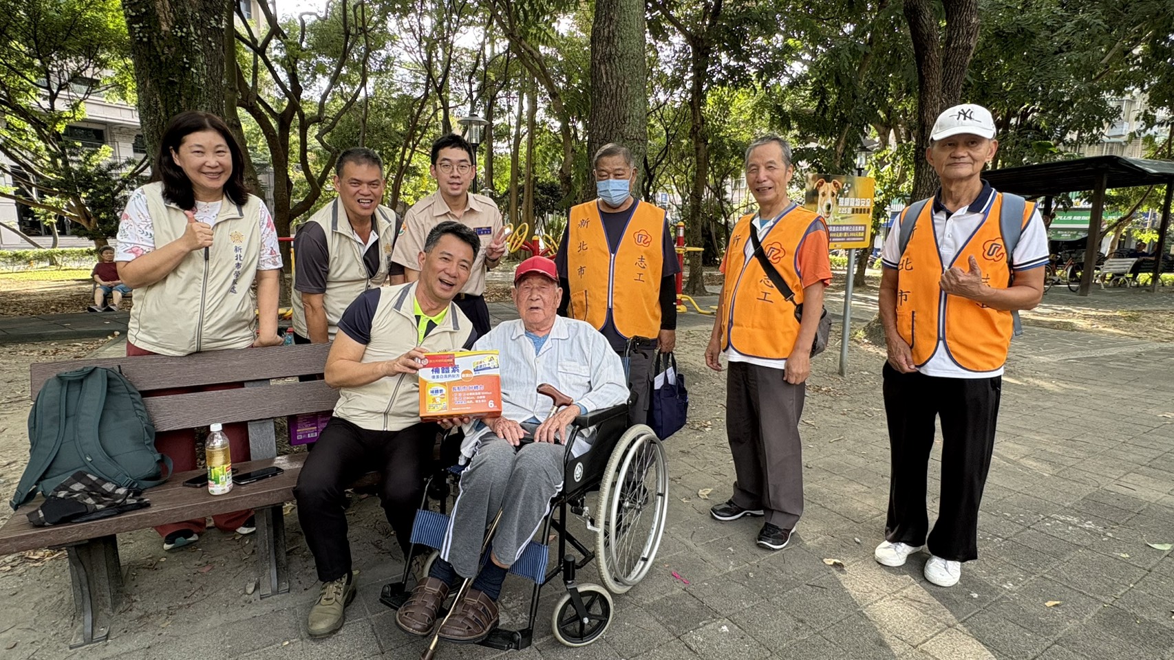 ▲處長陳立中(前排左)帶領榮欣志工陪96歲謝伯伯公園曬太陽,致贈營養品祝福重陽安康。/新北市榮服處提供。